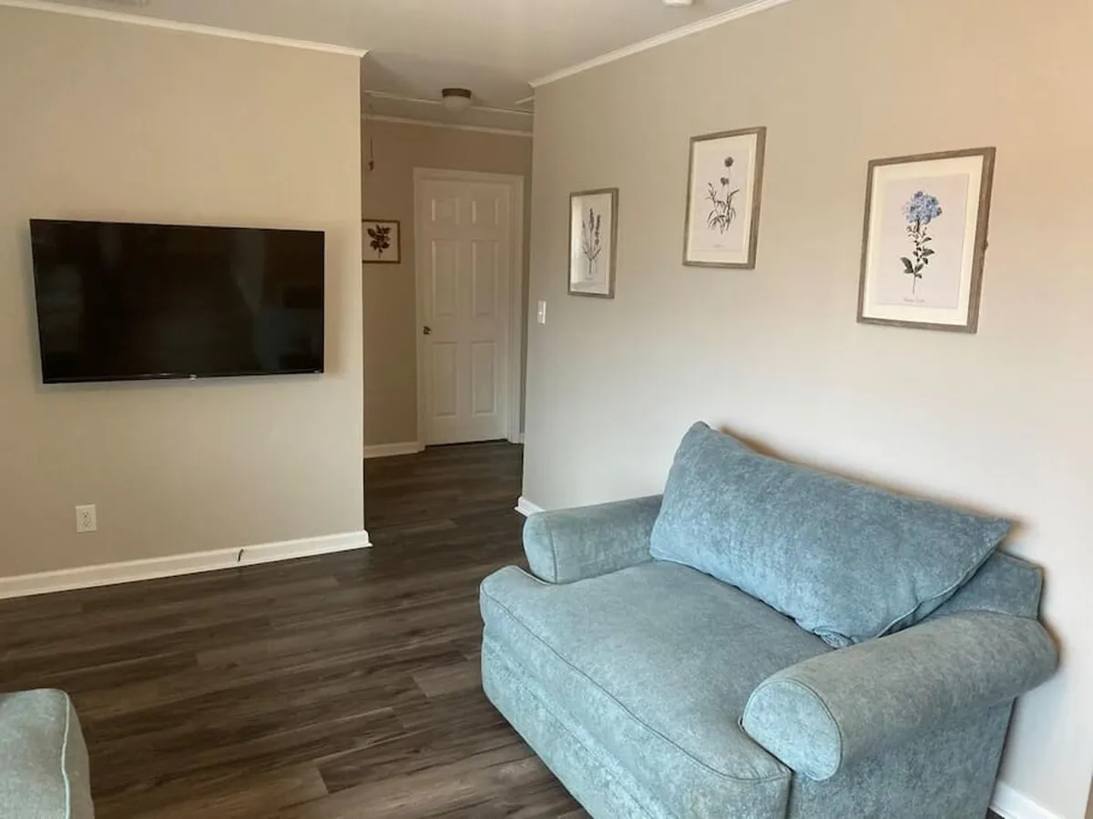 A comfortable living room setup with a plush sofa, a TV for entertainment, and framed artwork on the walls, creating a homey and restful atmosphere ideal for relaxing after outdoor adventures.