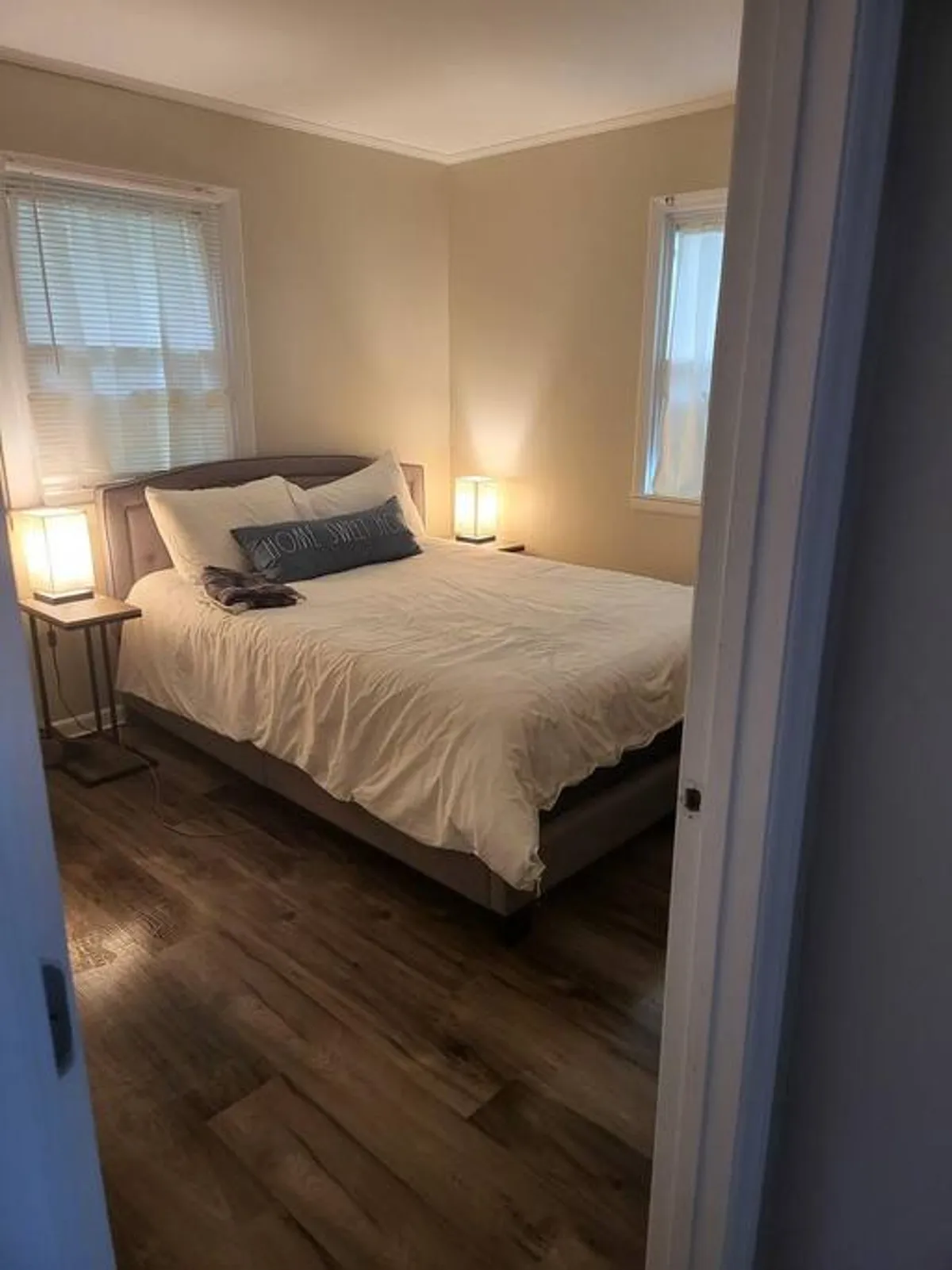 A serene bedroom featuring a cozy bed with soft linens, nightstands topped with lamps, and a window that lets in natural light. The overall mood is restful, with elements like books for bedtime reading and gentle lighting creating a welcoming retreat.