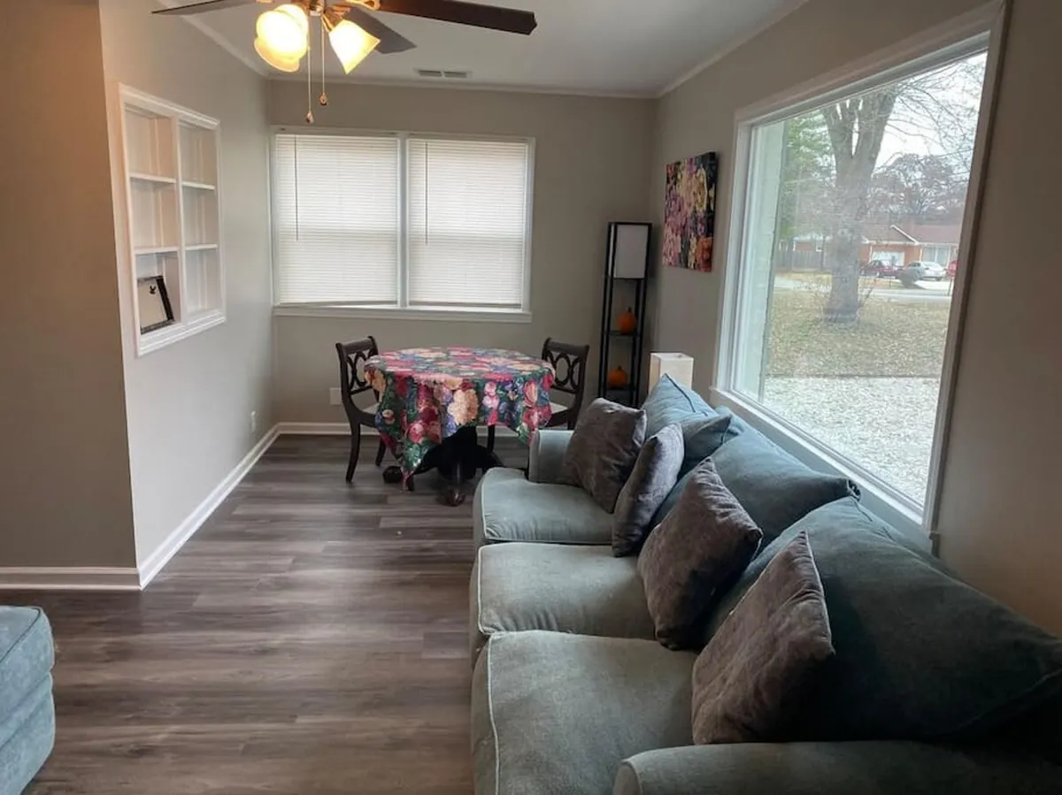A cozy zone with large windows, a colorful tablecloth on the dining table, and a comfortable couch, inviting moments of connection or personal downtime. The setup provides a cheerful backdrop for meals, conversations, or simply soaking up the view.