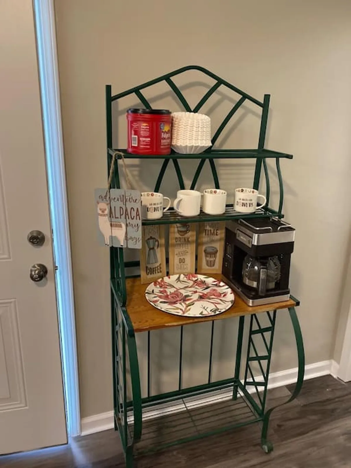 A close-up view of a coffee maker, mugs, and a neatly organized shelf with decor, suggesting a comfortable spot for morning routines or casual conversations over coffee.
